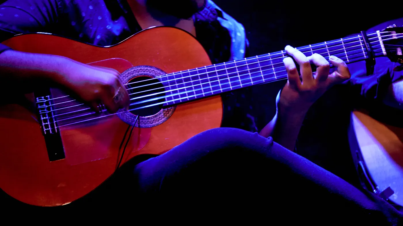 Close-up of a flamenco guitarist’s hands on the strings under stage light